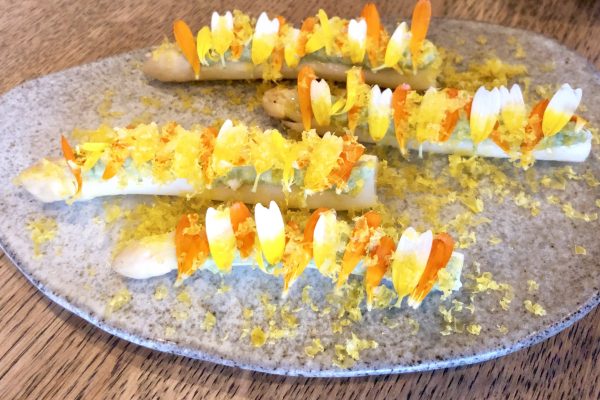 White asparagus spear with cured egg yolk and fresh flowers, at Amass